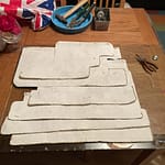 Rows of white rectangular canvas pieces arranged on a wooden surface, representing the cover canvasses for the Samsaragammon project's holographic art installation."